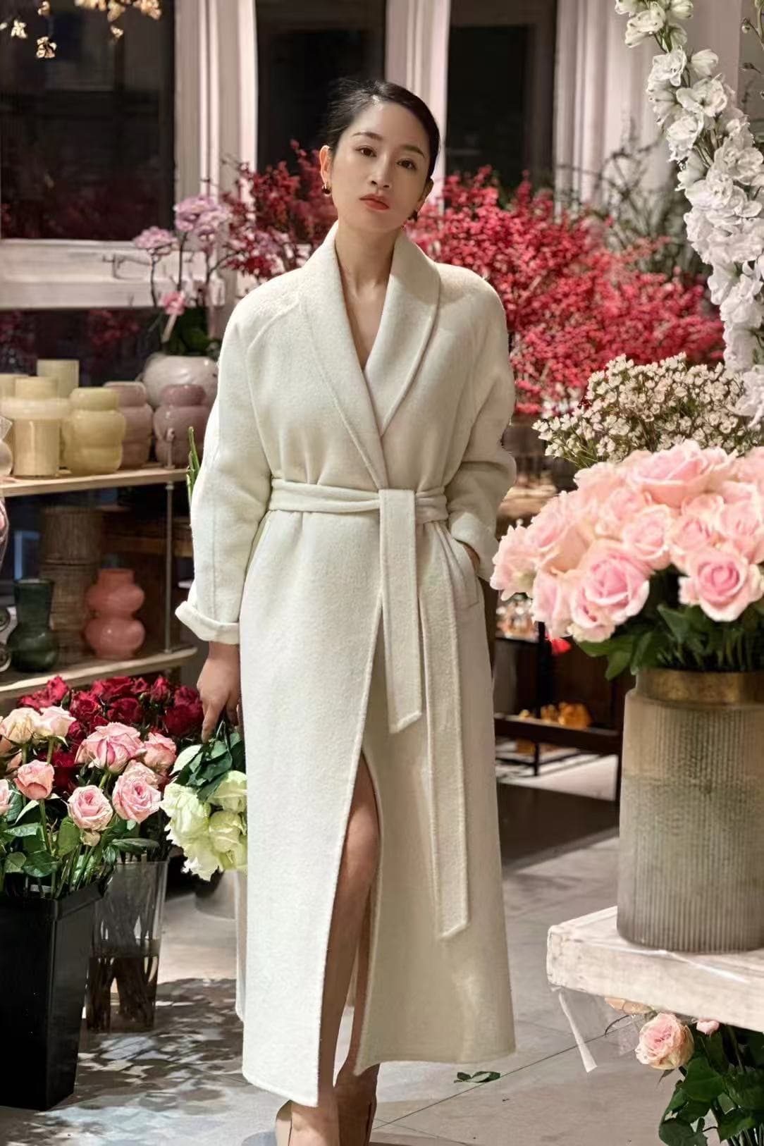 Model in an ivory wrap cashmere coat styled inside a floral studio.