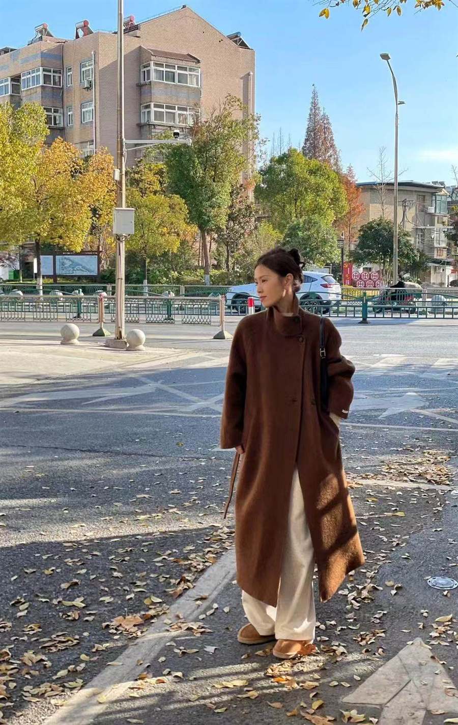 Model wearing a camel long cashmere coat in an autumn street setting.