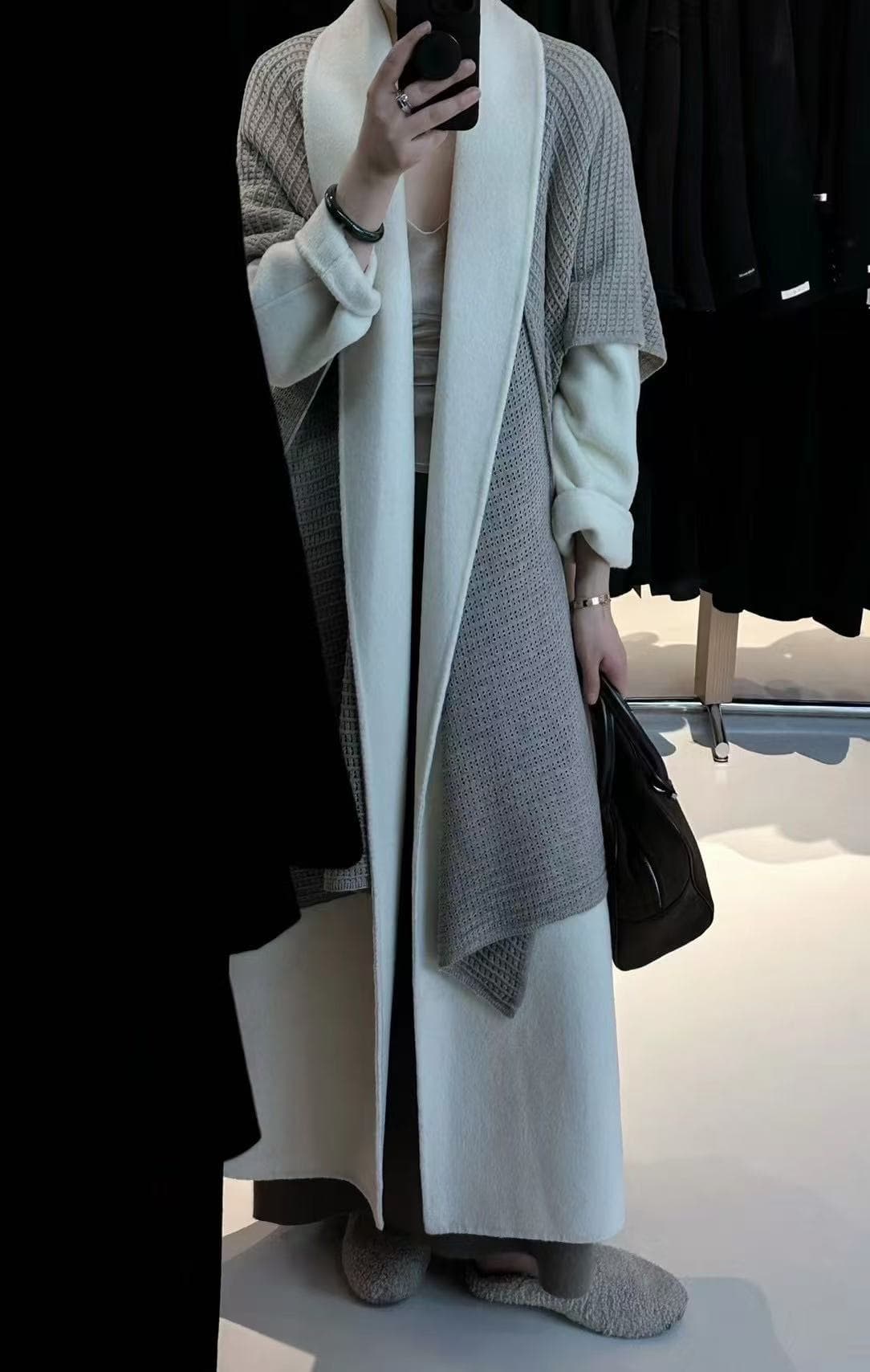 Cream coat layered in a quiet showroom styling setup.